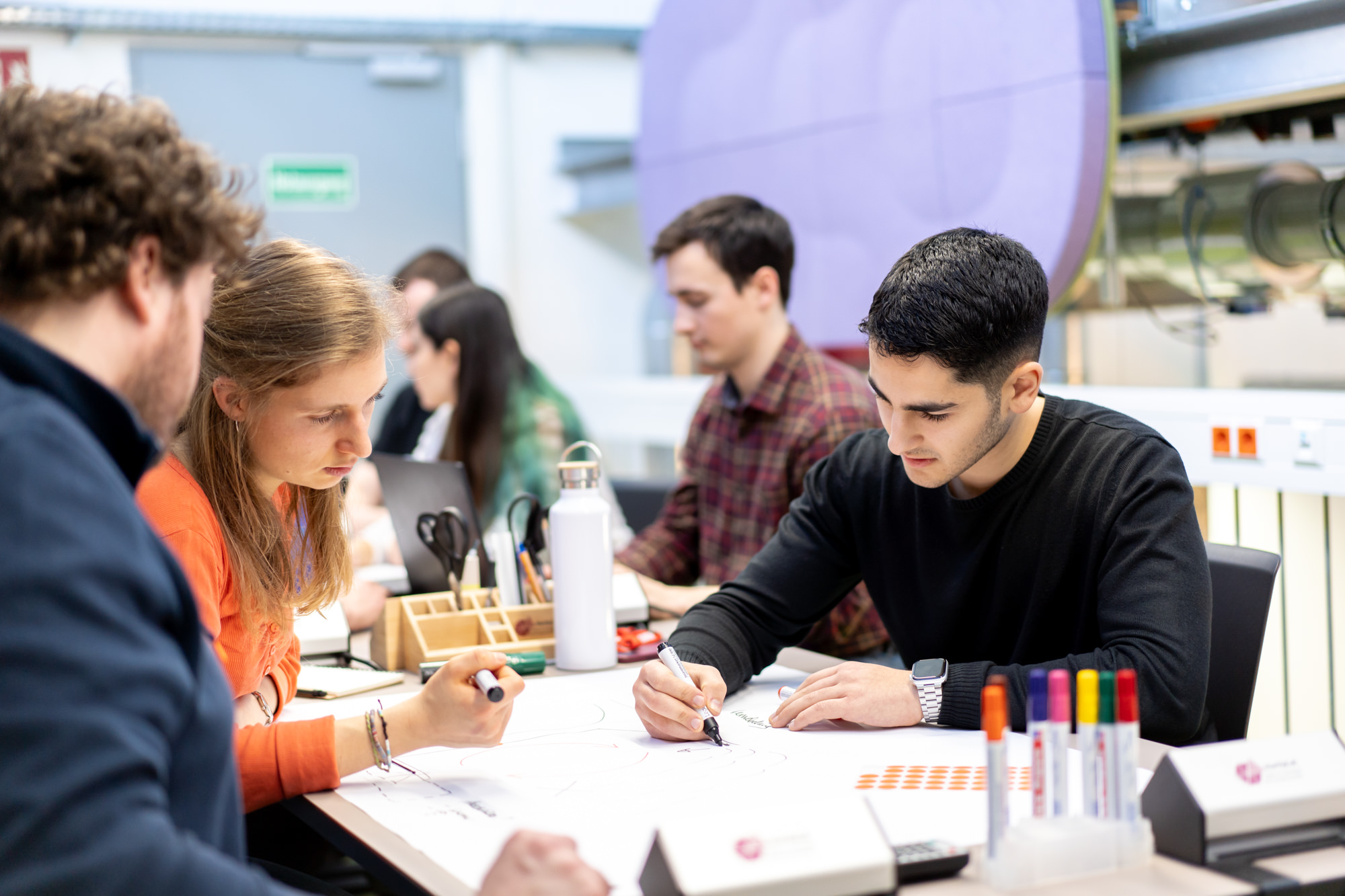 Gruppe von Studierenden arbeiten gemeinsam an einem Tisch